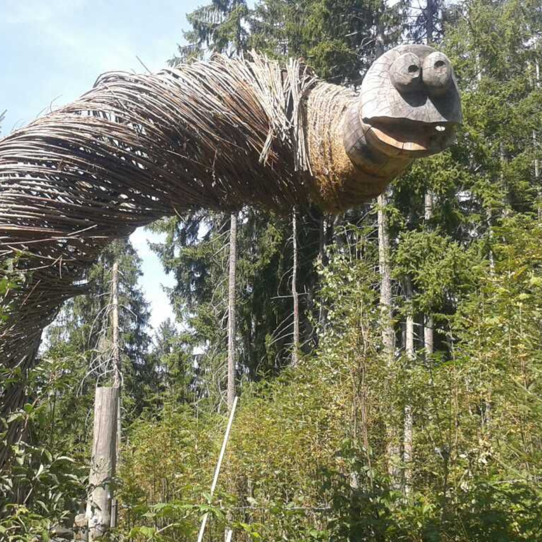 Beliggende i en skovs grønne omgivelser, har denne skulptur, der minder om de mytiske skabninger, man kunne forestille sig på en Sommerferie i Westendorf, vævede grene, der danner en stor slange med et udskåret træhoved, store øjne og en åben mund blandt høje træer.