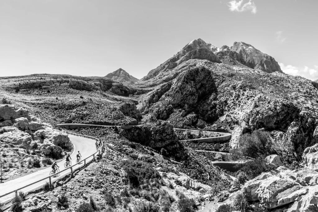 Cyklister på vejen ved Sa Calobra i Mallorcas bjerglandskab.
