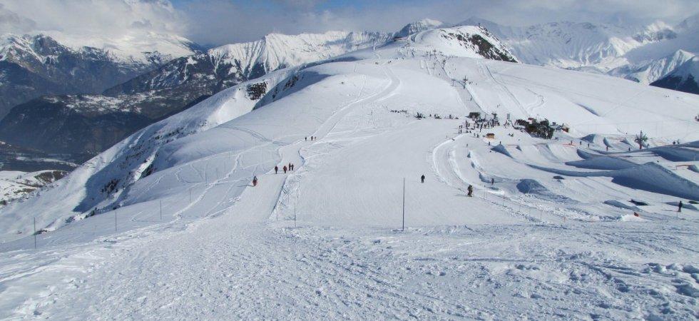 Ett snöigt bergslandskap med skidbackar, utspridda skidåkare och stolliftar sätter scenen för en perfekt skiferie i La Toussuire. Snötäckta toppar och avlägsna berg fyller bakgrunden under en molnig himmel.