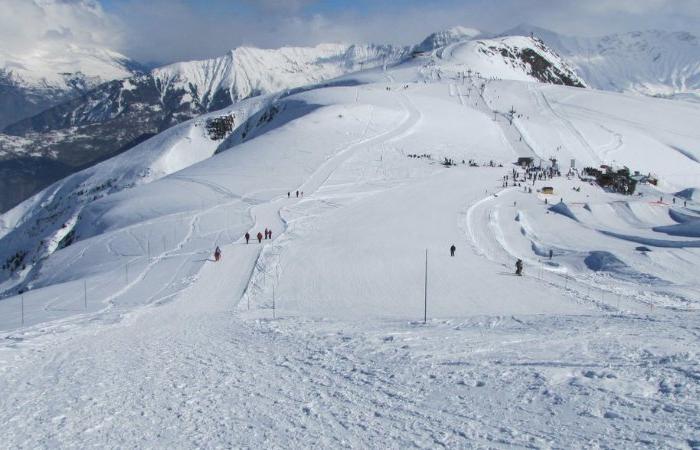 Ett snöigt bergslandskap med skidbackar, utspridda skidåkare och stolliftar sätter scenen för en perfekt skiferie i La Toussuire. Snötäckta toppar och avlägsna berg fyller bakgrunden under en molnig himmel.
