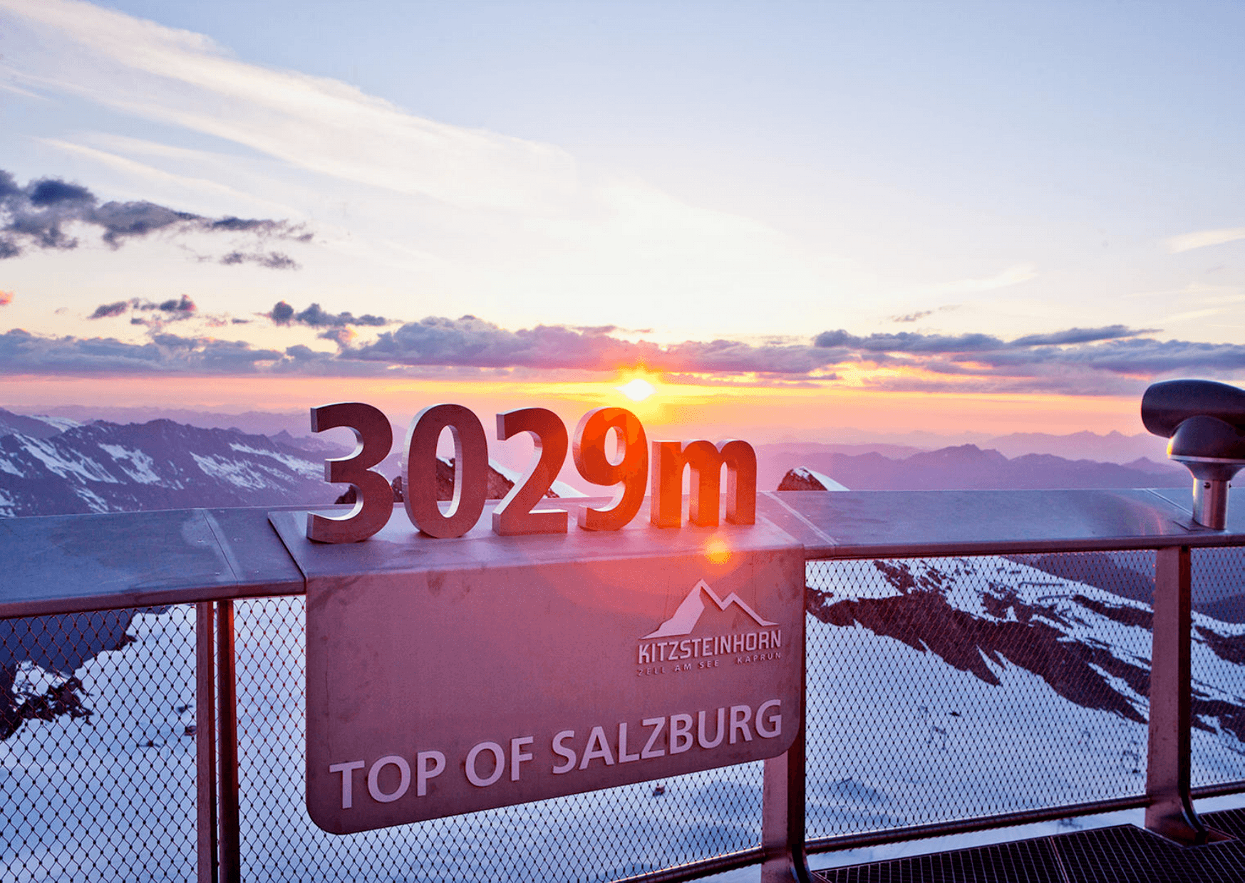 Oplev den betagende udsigt over solopgangen fra Kitzsteinhorn-gletsjeren på toppen af Salzburg, Østrig. På 3029m er snedækkede bjerge og skyer badet i solens varme skær – en perfekt start på dit skiferieeventyr, kun en kort rejse fra Wagrain.